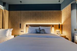 a bedroom with a large white bed with a headboard at Magnes Hotel in Volos