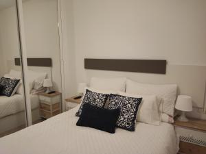 1 dormitorio con cama blanca con almohadas y espejo en Calesapart Tranquilidad con vistas al mar, en Candelaria