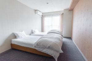 um quarto com 2 camas com lençóis brancos e uma janela em CHENDA INTERNATIONAL HOTEL em Minami Uonuma