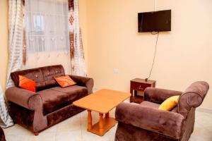 a living room with two couches and a tv at Exotic Inn and Apartments in Kampala