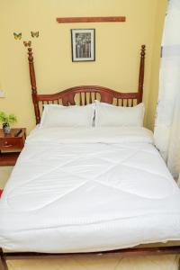 a large white bed with white sheets and pillows at Exotic Inn and Apartments in Kampala