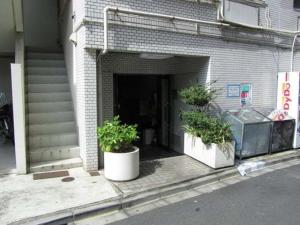 tres macetas sentadas frente a un edificio en Shibuya Hana House, en Tokio