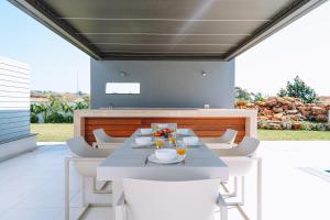 a dining room with a table and white chairs at Vivo Mare Beachfornt Villas - Azure in Ayia Napa