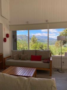 Una sala de estar con un sofá y una ventana grande. en Moderna casa en el bosque, en San Martín de los Andes
