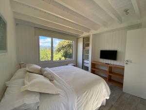 Un dormitorio con una gran cama blanca y una ventana. en Moderna casa en el bosque, en San Martín de los Andes