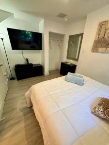 una camera con un grande letto bianco e una TV a schermo piatto di Quiet & Centrally located House - PRIVATE PARKING, LAUNDRY AND STORAGE FOR LUGGAGE a Miami