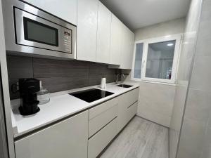 eine Küche mit weißen Schränken und einer Mikrowelle in der Unterkunft Apartamento en pleno centro de Valladolid in Valladolid