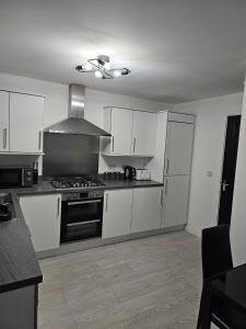 a kitchen with white cabinets and a stove top oven at Superb 3 Bed Home Away from Home in Glasgow, just off M8 with free parking in Steps