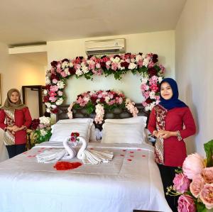 twee vrouwen die naast een groot bed met bloemen staan bij Keraton Krakatoa in Banten