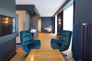 une salle d'attente avec des chaises bleues, une table et une télévision dans l'établissement Artis Loft Hotel, à Radziejowice