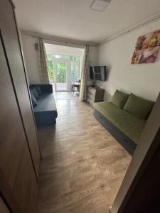 ein Wohnzimmer mit einem grünen Sofa und einem TV in der Unterkunft Zamárdi Parti Apartman in Zamárdi