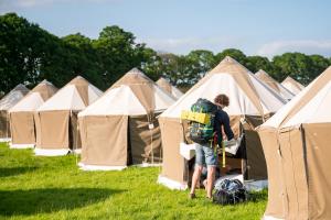 Un uomo in piedi davanti a una fila di tende di Festival Yurts Hay-on-Wye a Hay-on-Wye