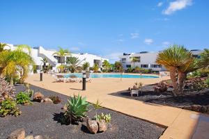 a resort with a pool and palm trees and buildings at The Garden Secret in Villaverde