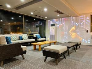 - un hall avec des canapés, des tables et un grand écran dans l'établissement CHENDA INTERNATIONAL HOTEL, à Minami Uonuma