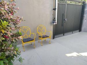 Duas cadeiras amarelas sentadas num pátio com um portão em Casa aconchegante em Sao Jose do Rio Preto