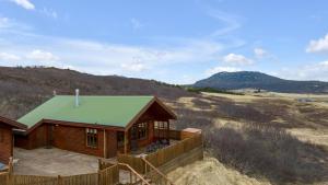 a log cabin with a green roof in a field at Summer House with Stunning Mountain Views in Úthlid