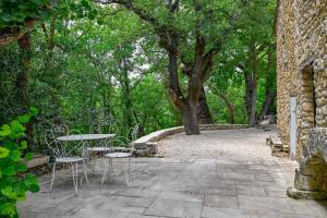 a patio with a table and chairs and trees at Santonne in Apt