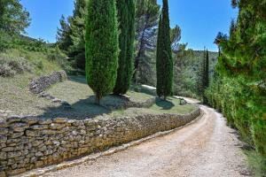 a dirt road with trees and a stone wall at Santonne in Apt