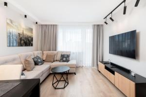 uma sala de estar com um sofá e uma televisão em Bronowice Cosy Apartment em Cracóvia