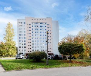 um grande edifício branco com carros estacionados num parque de estacionamento em Bronowice Cosy Apartment em Cracóvia