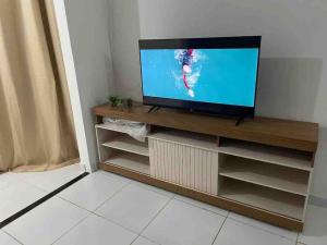 una TV a schermo piatto seduta sopra un centro di intrattenimento in legno di Apto com 3 dormitórios com ar, Vista para praia em Morro Branco - Fortaleza a Beberibe
