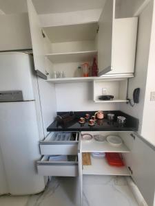 una pequeña cocina con armarios blancos y nevera. en Apê Gourmet Comfort, en Cuiabá