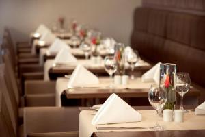 une rangée de tables avec des verres à vin et des serviettes dans l'établissement Novotel Düsseldorf City West, à Düsseldorf