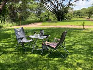 two chairs and a table in the grass at Lorato Lodge and Camping in Muchenje