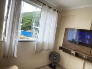 sala de estar con TV de pantalla plana y ventana en Centro de poços de caldas en Poços de Caldas