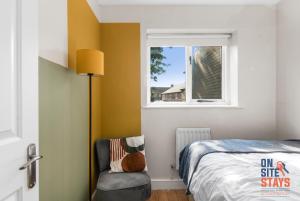 a bedroom with a bed and a chair and a window at OnSiteStays - EARLY CHECK IN AUGUST - Modern 3 bed House, 2 x Parking, Garden, WIFI & dishwasher in Bromley