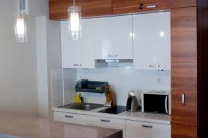 a kitchen with white cabinets and a sink and a microwave at Apartament Cafe Del Mar in Świnoujście