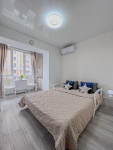 a white bedroom with a large bed with blue pillows at Лайт студия на Южном вокзале in Kharkiv