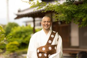 een man in een kimono die voor een gebouw staat bij Temple Hotel 南アルプス法源寺 in Minami Alps
