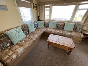 a living room with a couch with pillows and a table at Eagle 4a, Scratby - California Cliffs, Parkdean, sleeps 8, bed linen and towels included, pet friendly and close to the beach in Great Yarmouth