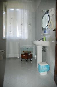 Baño blanco con lavabo y espejo en Affittacamere Villa Delia, en Lucca