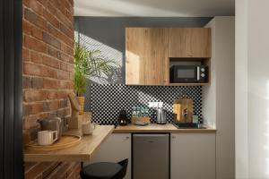 a kitchen with white cabinets and a brick wall at Movo Underwall Old Town Apartment in Warsaw
