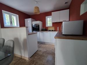 uma cozinha com electrodomésticos brancos e paredes vermelhas em Domaine de l'Arbre Doré em Lèzan