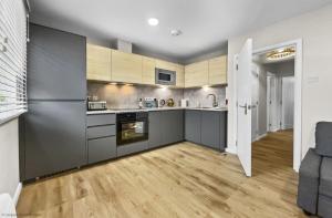 a kitchen with gray cabinets and a wooden floor at Whitsun 1,5 in Gosport
