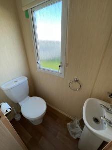 a bathroom with a toilet and a sink and a window at E4A, Three bedroom caravan - California Cliffs, Parkdean Resort, Scratby - Sleeps 8, bed linen and towels included - Pet Friendly - only 300m from the beach! in Great Yarmouth +14 photos