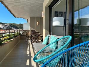 濱海托薩的住宿－Magnificent apartment at the sea front of Tossa de Mar，阳台设有蓝色长椅,阳台上设有蓝色长椅。