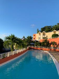 een zwembad in een resort met palmbomen en gebouwen bij La Fraîche Rosé in La Trinité