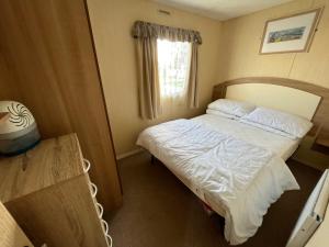 a small bedroom with a bed and a window at E4A, Three bedroom caravan - California Cliffs, Parkdean Resort, Scratby - Sleeps 8, bed linen and towels included - Pet Friendly - only 300m from the beach! in Great Yarmouth