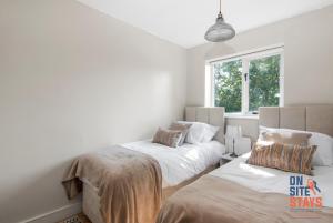 sypialnia z 2 łóżkami i oknem w obiekcie OnSiteStays - EARLY CHECK IN MAY - Modern 3 bed House, 2 x Parking, Garden, WIFI & dishwasher w mieście Bromley