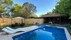 a swimming pool in a yard with two white chairs next to it at Aromos Lodge ll - Chacras de Coria in Ciudad Lujan de Cuyo