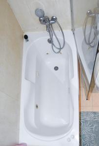 Aparment sierra Guadalupe في مدريد: حوض استحمام أبيض في حمام مع دش