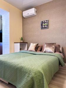 a bedroom with a large bed with a green comforter at Эко студия на Южном вокзале in Kharkiv