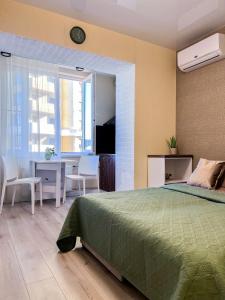 a bedroom with a green bed and a table and chairs at Эко студия Вокзал Харьков-Пассажирский in Kharkiv