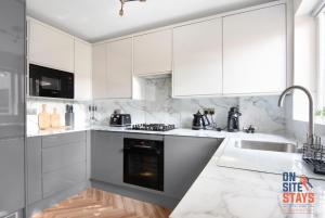 Biała kuchnia z białymi szafkami i zlewem w obiekcie OnSiteStays - EARLY CHECK IN MAY - Modern 3 bed House, 2 x Parking, Garden, WIFI & dishwasher w mieście Bromley