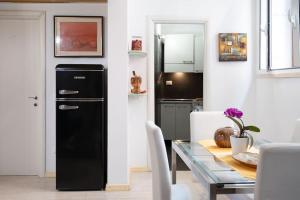 een keuken met een zwarte koelkast naast een tafel bij Casa Bartolomeo - Loft in Trastevere in Rome