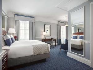 a hotel room with a bed and a desk and a mirror at Fairmont Copley Plaza in Boston